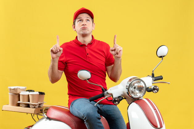 摩托车顶视图混乱的年轻人穿着红色上衣和帽子 交付指示黄色背景上的命令男子人指向