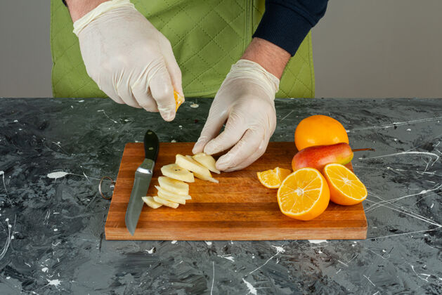 烹饪男手戴手套 把柠檬汁挤进木板上的苹果里混合切手