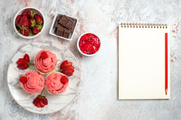 饼干白色表面有果酱和巧克力棒的粉色草莓蛋糕俯视图茶浆果条子