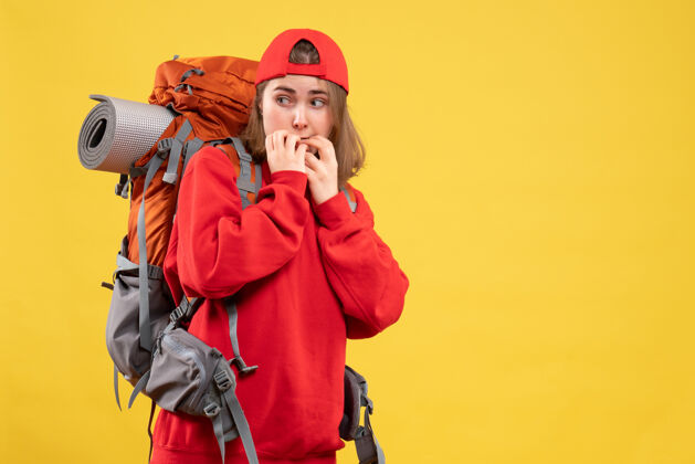 前面正面图穿着红色背包站在黄色墙壁上的可爱旅行者女人成人脸人
