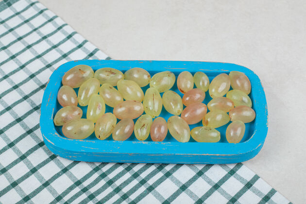 成熟蓝色盘子上的一串葡萄和桌布有机桌布水果