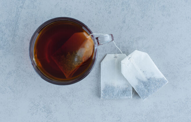 配料两个茶包旁边是一杯茶放在大理石上美味的暖暖的茶