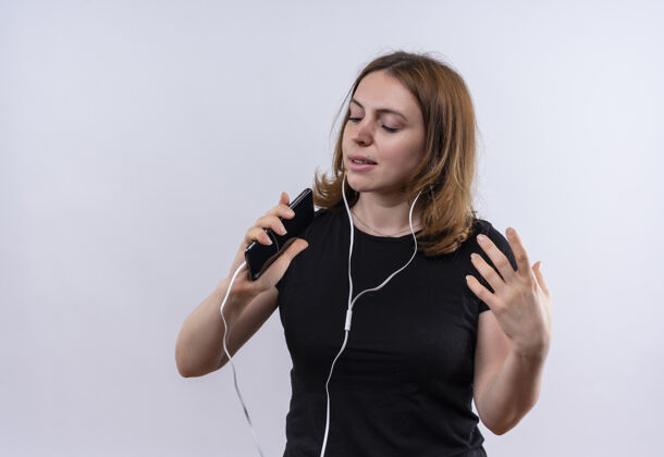 复制唱歌的年轻随意的女人戴着耳机 用手机作为麦克风 在隔离的空白处用拷贝空间麦克风休闲空间