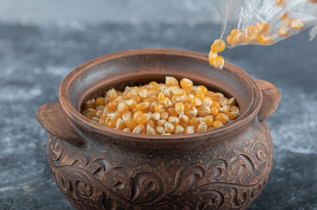 生的用手把一碗未煮熟的爆米花种子放在大理石上膳食食物豆类