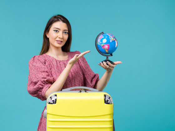 地球前景度假女抱着蓝色背景上的小地球仪出海度假旅行避暑女蓝色假期旅行