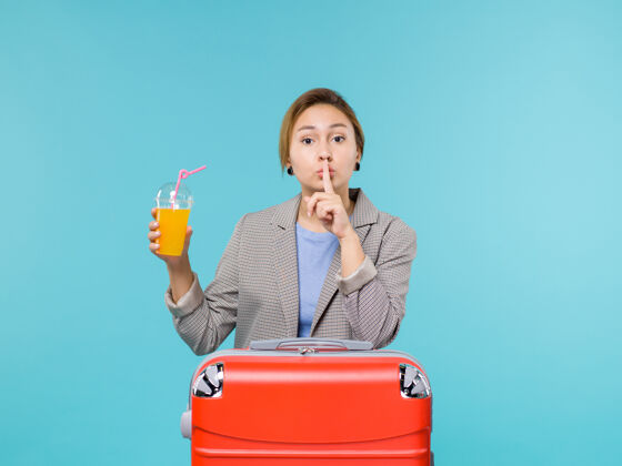 人前视图女性在度假与她的红色袋子举行新鲜果汁蓝色背景海上度假飞机旅行微笑红色沉默