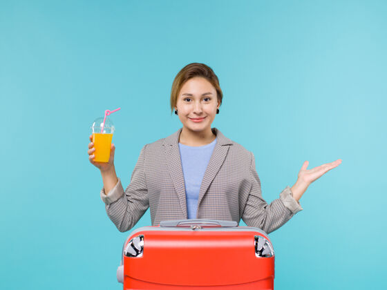 果汁正面图：度假中的女性 带着红色的袋子 拿着新鲜的果汁 在蓝色的背景上 度假飞机航行 海上旅行人旅行风景