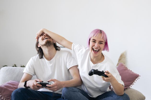 享受可爱的情侣在沙发上玩电子游戏科技数字房子
