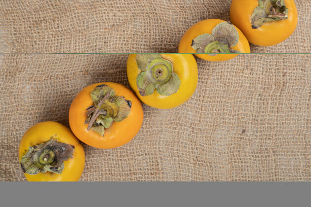 自然一堆熟的美味柿子放在粗麻布上水果柿子配料