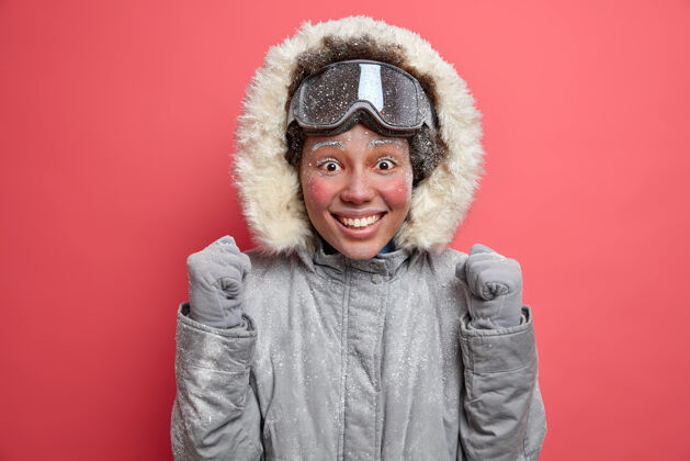 霜冻情绪积极的女人举起拳头 迫不及待地去滑雪板表达快乐的情绪享受冬天的时间和积极的休息穿暖和的夹克和滑雪镜快乐的女滑雪者人类心情温度