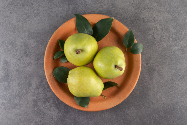 饮食在石头表面放上一盘成熟健康的梨成熟营养水果