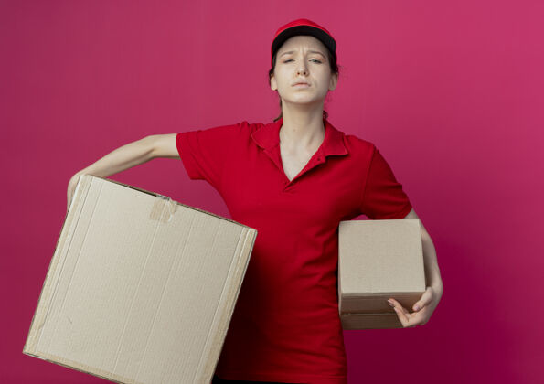女孩一个年轻漂亮的送货女孩 穿着红色制服 戴着帽子 手里拿着一个盒子 背景是深红色的深红色不愉快漂亮