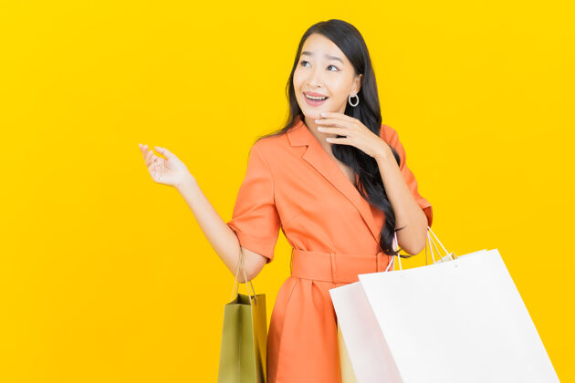 Shopper肖像美丽的亚洲年轻女子微笑购物袋上的黄色LadyPurchasePayment