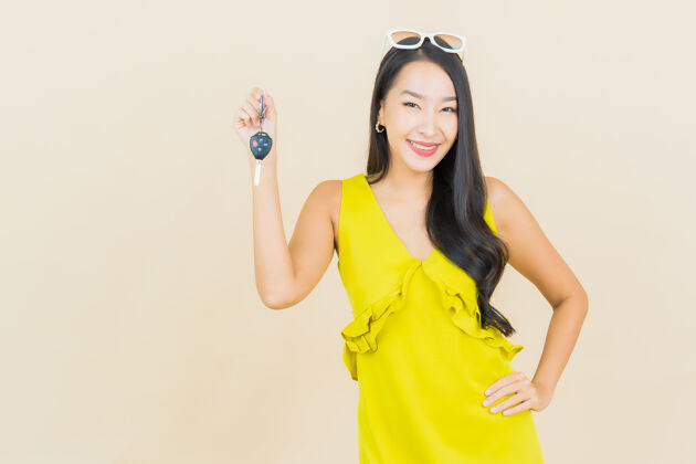 服务肖像美丽的亚洲年轻女子微笑着把车钥匙放在彩色墙上人经销商人