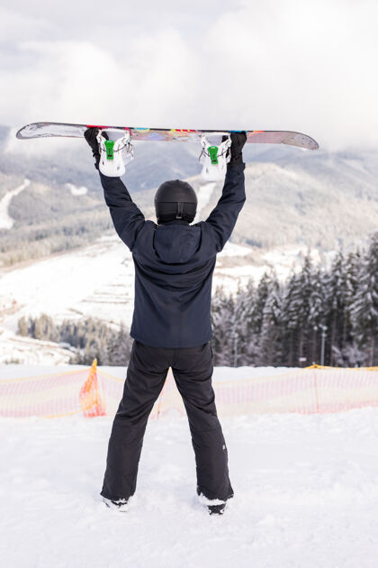 夹克快乐的人头顶着滑雪板站在山顶上乐趣成人运动