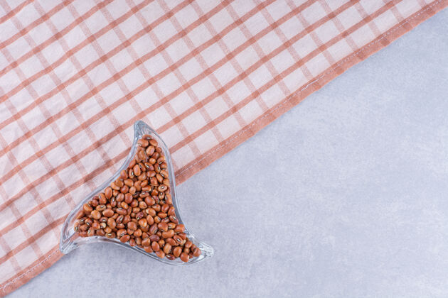 干的红豆在一个小的 三角形的盘子里放在桌布上 放在大理石表面桌布料理有机