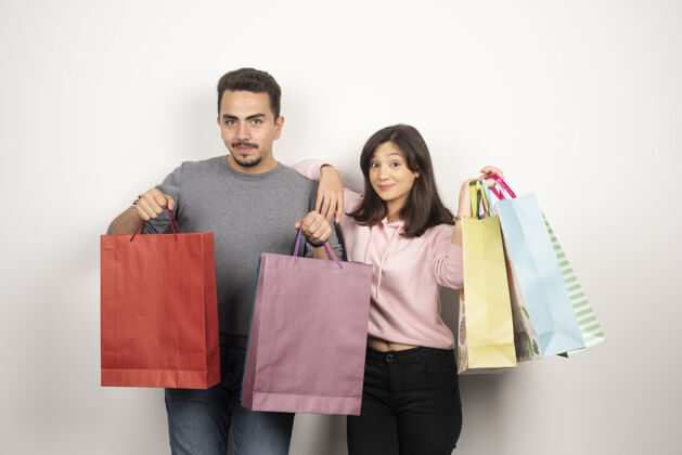 购物狂带着购物袋摆姿势的快乐情侣女人购物袋抱着