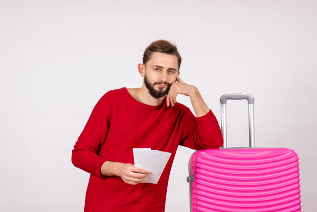 风景正面图：年轻男性 带着粉色包 手持机票 在白墙上航行 飞行旅行 旅游度假 照片感慨成人飞行情绪