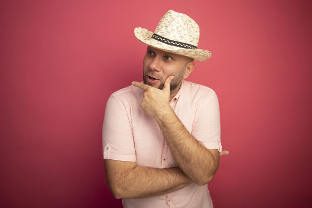 壁板惊讶的看着身边中年秃头男子穿着粉色t恤 戴着粉色帽子把手放在下巴上隔离开来中年粉色帽子