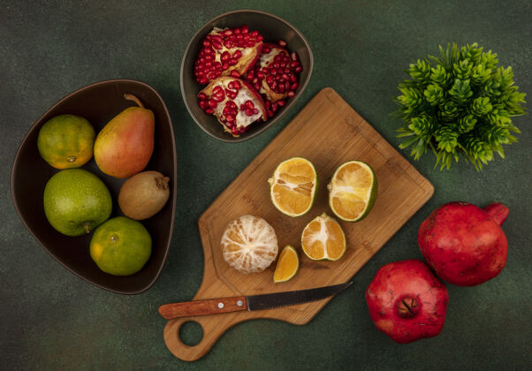 橘子顶视图打开和一半新鲜的橘子在一个木制的厨房板与刀打开石榴在一个碗板刀石榴
