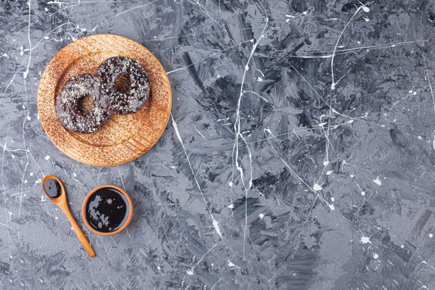 食物木制的巧克力甜甜圈盘 在大理石背景上撒椰子美味洒点糕点
