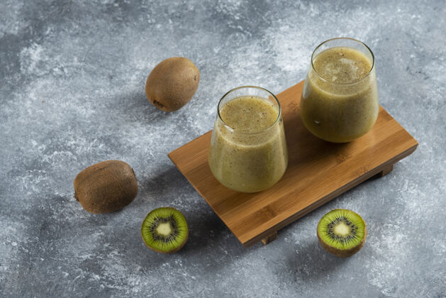 美味两杯美味的猕猴桃汁放在木板上绿色果汁提神