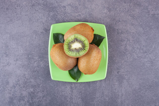 新鲜把美味的猕猴桃切成薄片 叶子放在绿色的盘子里半块分段异国风味