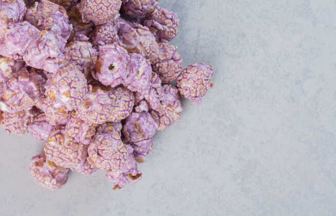 糖果一堆涂着糖果的紫色爆米花放在大理石表面玉米美味大衣