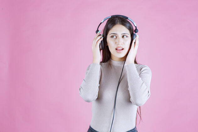 成人戴着耳机看音乐的女孩 看起来很严肃姿势中立低