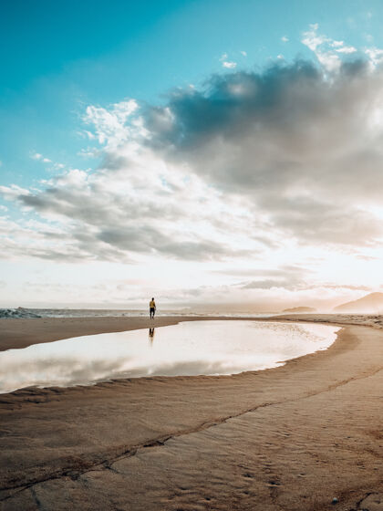 阳光日落时分 一个人在多云的沙滩上锻炼 这是一幅美丽的风景画站立白天太阳
