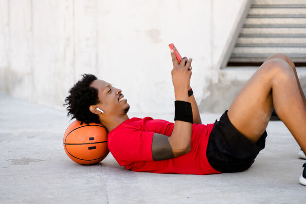 城市一个黑人运动员在户外工作后用手机放松自己年轻人运动训练
