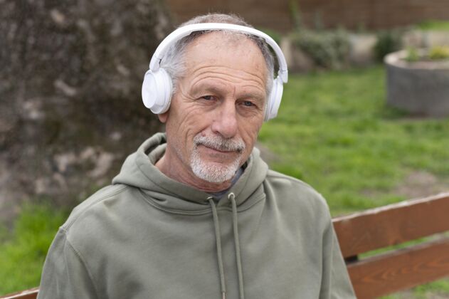 男人戴着耳机听音乐的现代老人生活方式水平耳机