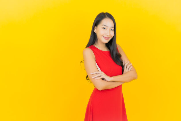 明亮肖像美丽的亚洲年轻女子穿着红色连衣裙微笑着行动在黄色的墙上紫色肖像中国人