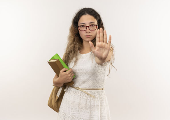 回来年轻漂亮的女学生戴着眼镜 背着书包 拿着书 看着镜头 做着手势 站在白色背景上 留着复印空间年轻眼镜漂亮
