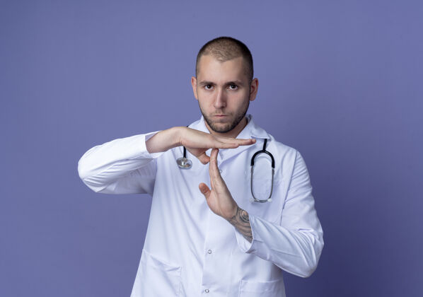 穿着年轻的男医生穿着医用长袍 脖子上戴着听诊器 在紫色背景上做着超时手势 并留有复印空间超时周围年轻