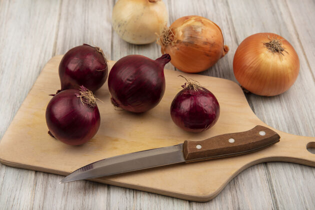 板顶视图紫红色的洋葱在一个木制的厨房板与黄色的洋葱隔离在灰色的木制背景刀刀灰色健康
