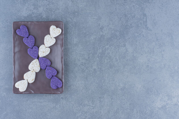 垃圾食品紫色和白色的饼干在黑板上 在大理石背景上不健康糕点配料