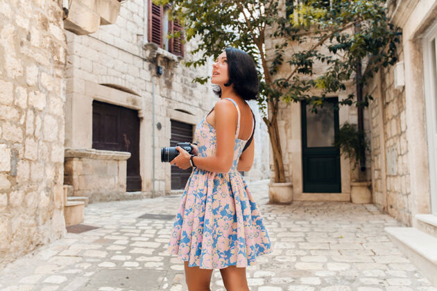 旅行在意大利老城区度假时 一个穿着长裙的漂亮女人在用相机拍照人度假街道