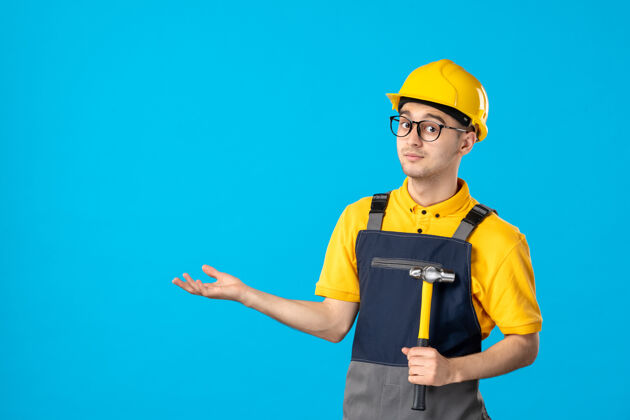 建筑工人前视图中的男性建筑工人穿着制服 手里拿着锤子在蓝色的表面上工人承包商服务