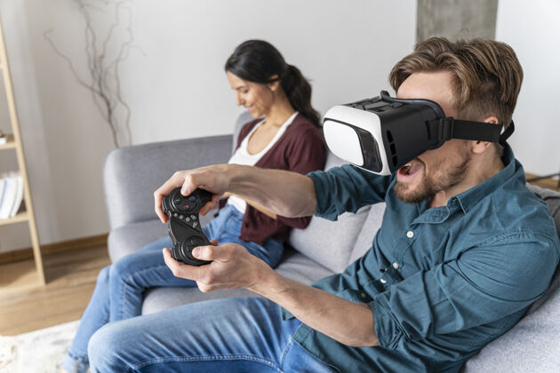 享受坐在沙发上玩虚拟现实耳机玩电子游戏的男人虚拟现实眼镜娱乐水平