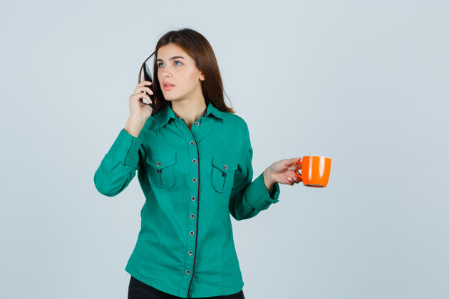 衬衫穿着衬衫的年轻女士端着橘黄色的茶杯 讲着手机 仔细地看着 眼前一亮眼睛治疗电话