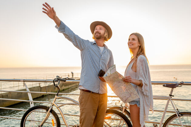 女人迷人的快乐情侣在夏天骑着自行车旅行 男人和女人金发波西米亚时尚时髦的嬉戏在一起男人二自行车