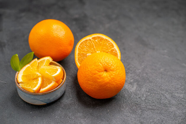 可食用水果黑暗的桌子上的整个和切碎的新鲜橙子的特写镜头完整柑橘成熟