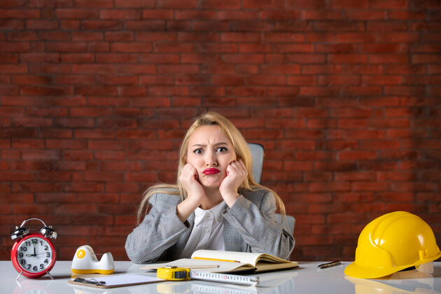 工作正面图年轻的女工程师坐在办公室里建筑坐着议程