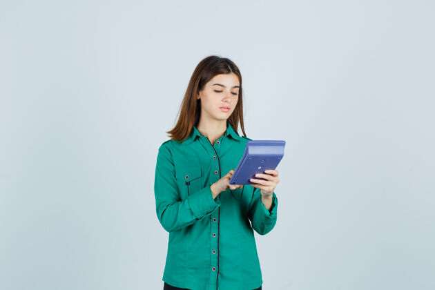 候选人身着绿色衬衫的年轻女士在计算器上计算的肖像 正看着忙碌的前视图专业人士水平职业