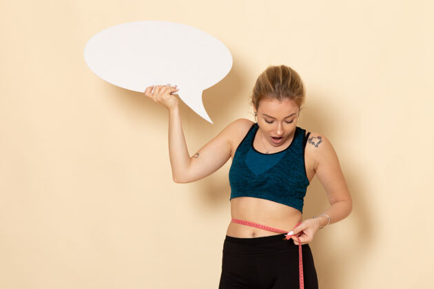健身正面图身穿运动服的年轻女性手持白色标志 测量着自己的身体运动美丽测量