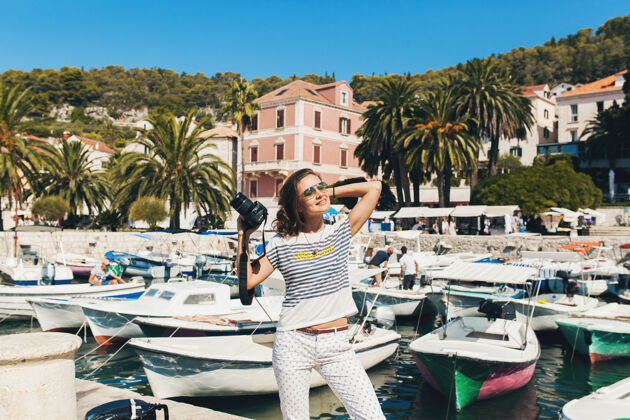城市一个穿着漂亮衣服的女人在欧洲海边度假 在游轮上用相机拍照乐趣太阳镜旅行