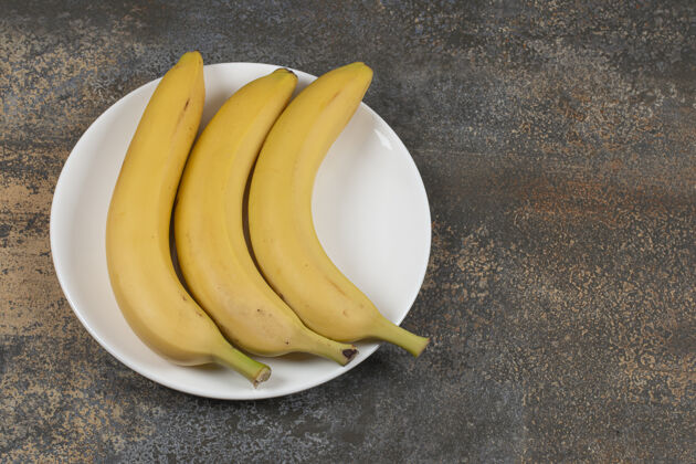 成熟白盘子里放三个熟香蕉有机热带新鲜