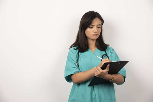 肖像女医生用听诊器在剪贴板上写字妇女工作医疗保健