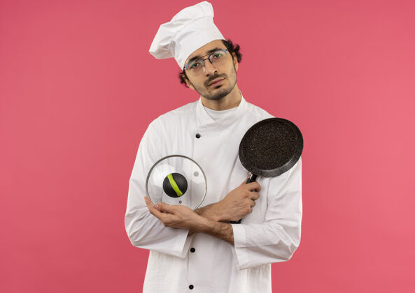 眼镜年轻的男厨师穿着厨师制服 戴着眼镜 拿着带盖的平底锅粉红薯条男